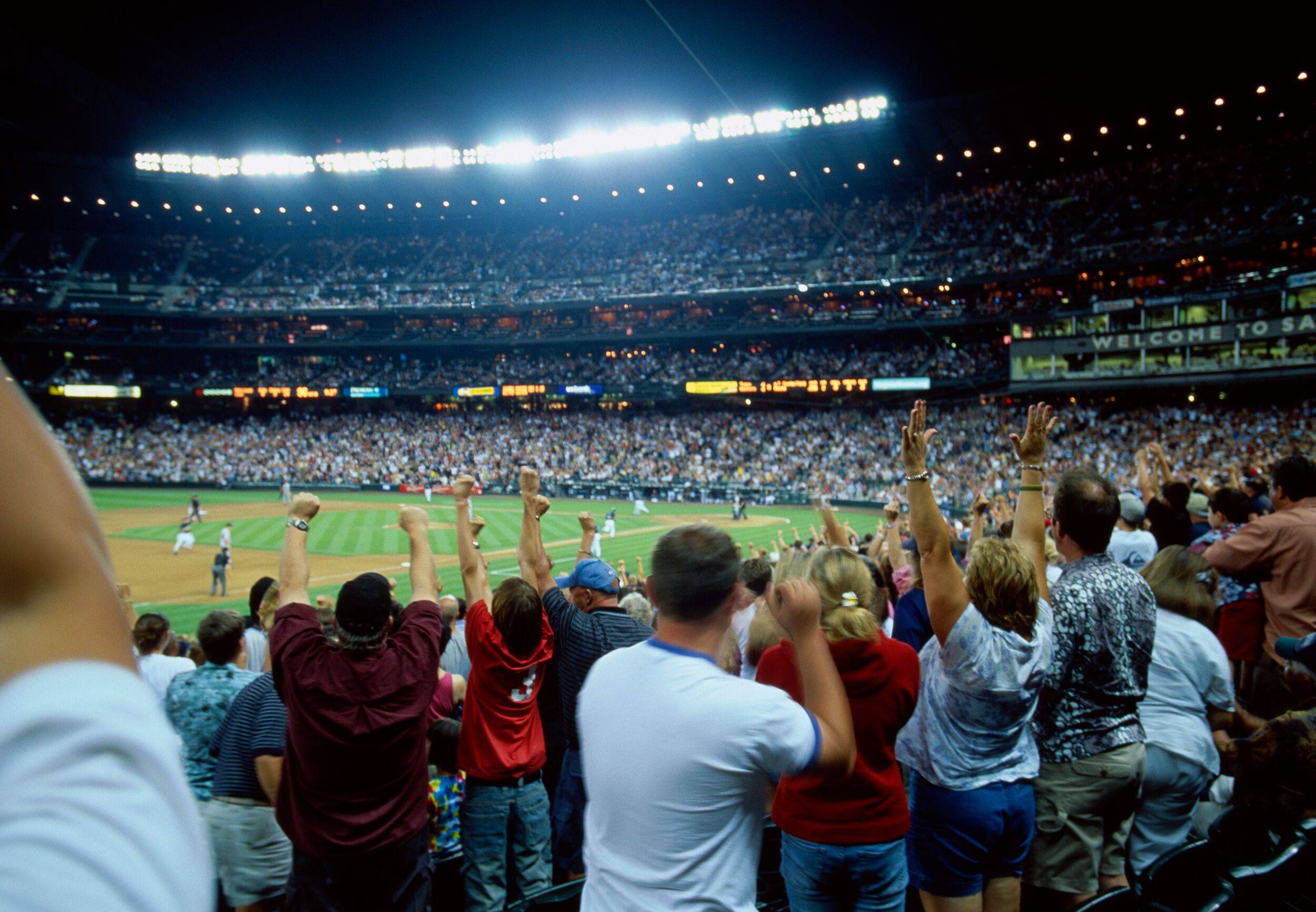 Crowd cheering at a night sporting event.