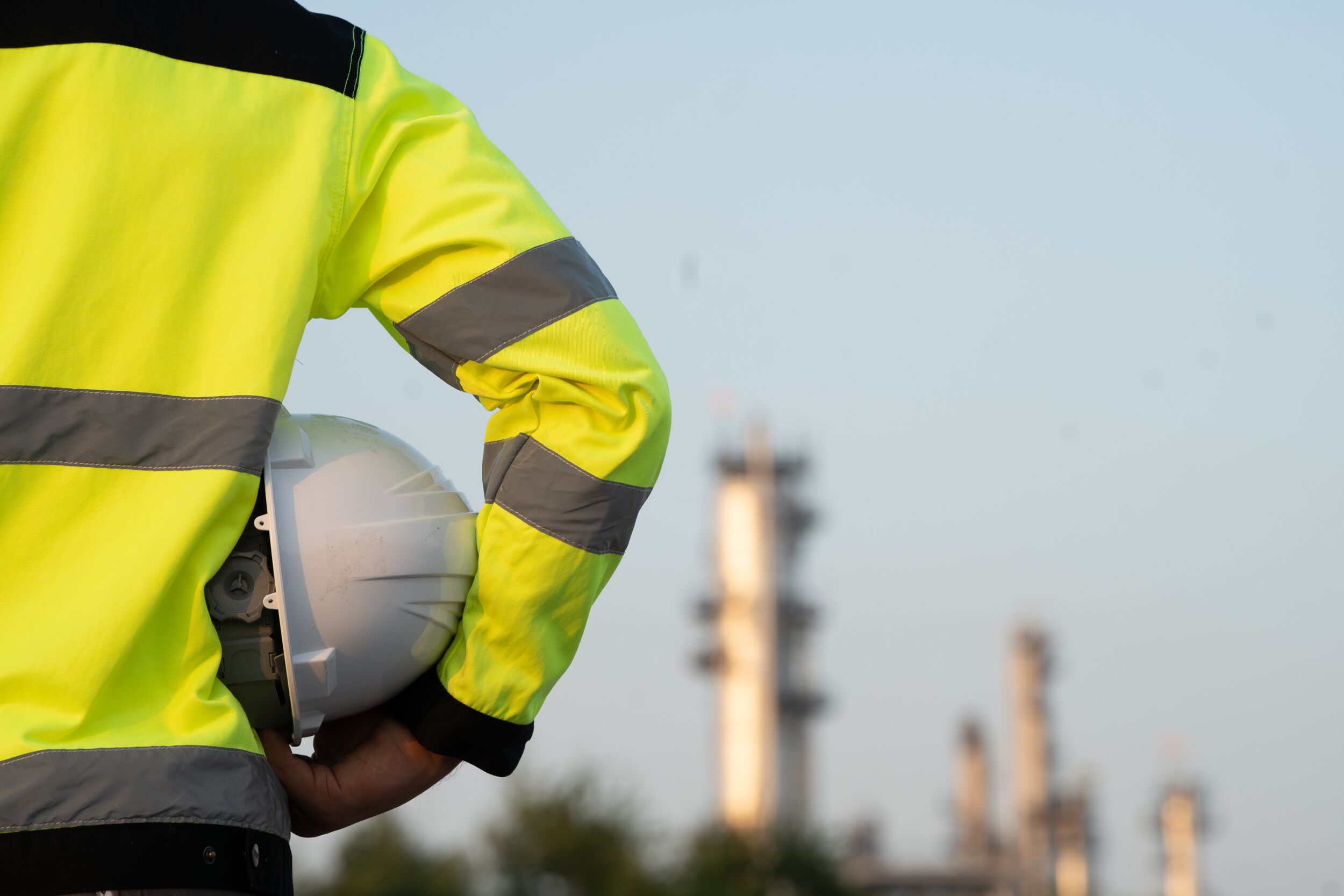 Egingeer working at oil and gas refinery plant taking a break and holding a helmet.