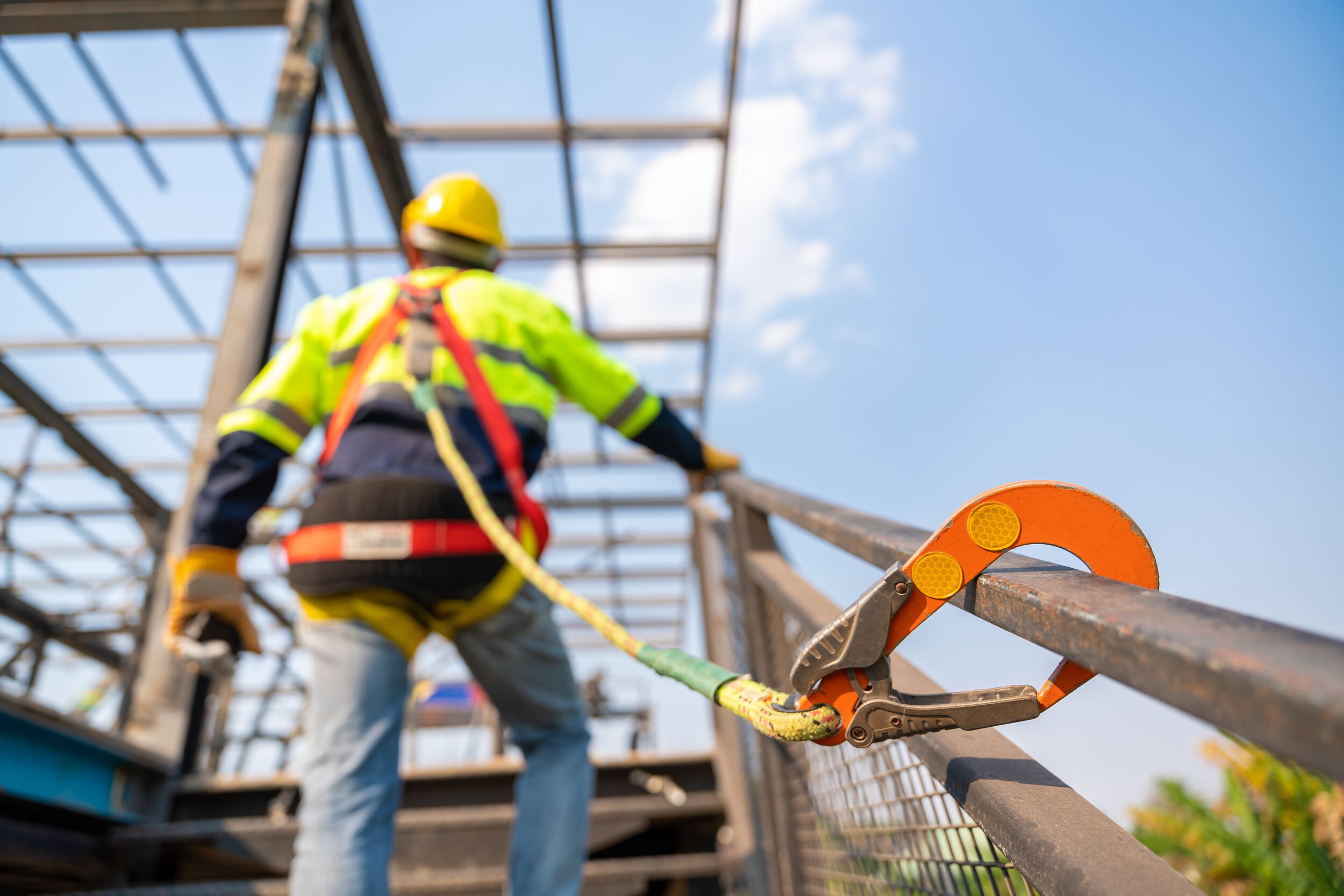 Construction workers are working on steel roof trusses.
