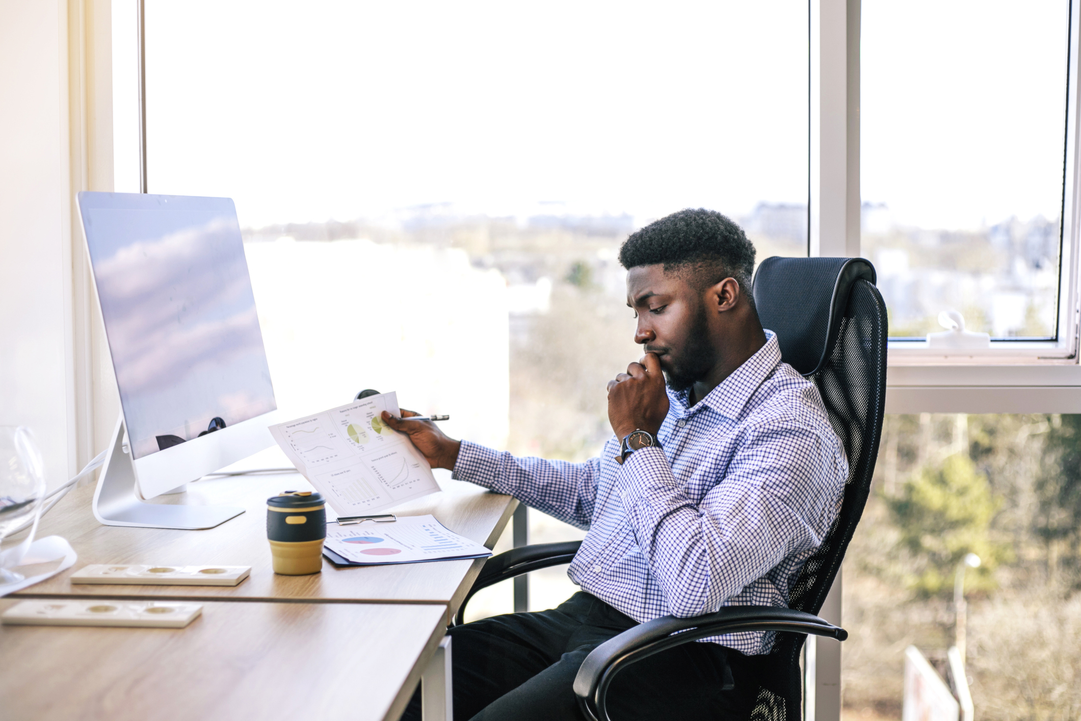 Black business man sitting at a desk looking at paperwork.
