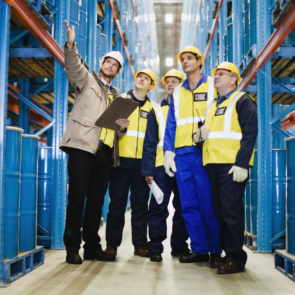 Factory workers looking at oil drums.
