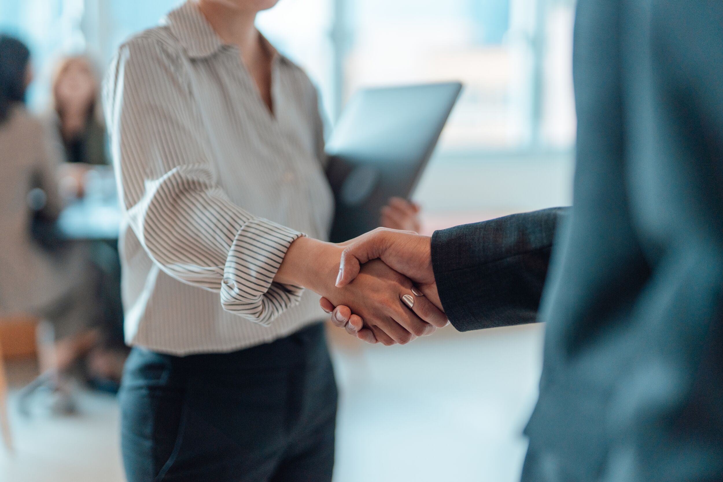 Business people standing in a modern office, shaking hands after having a successful meeting.