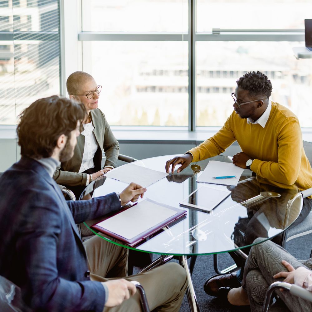 Coworkers meeting around a glass table.