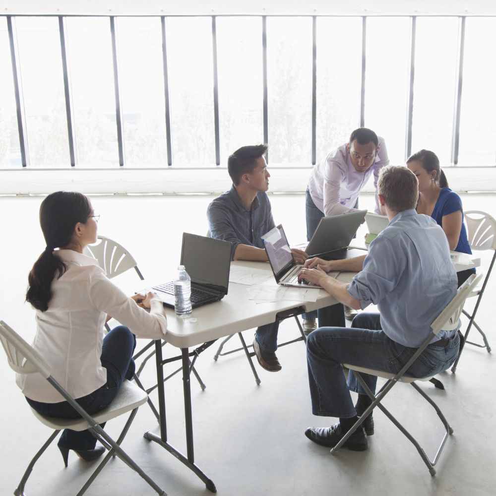 Employee meeting around white table.