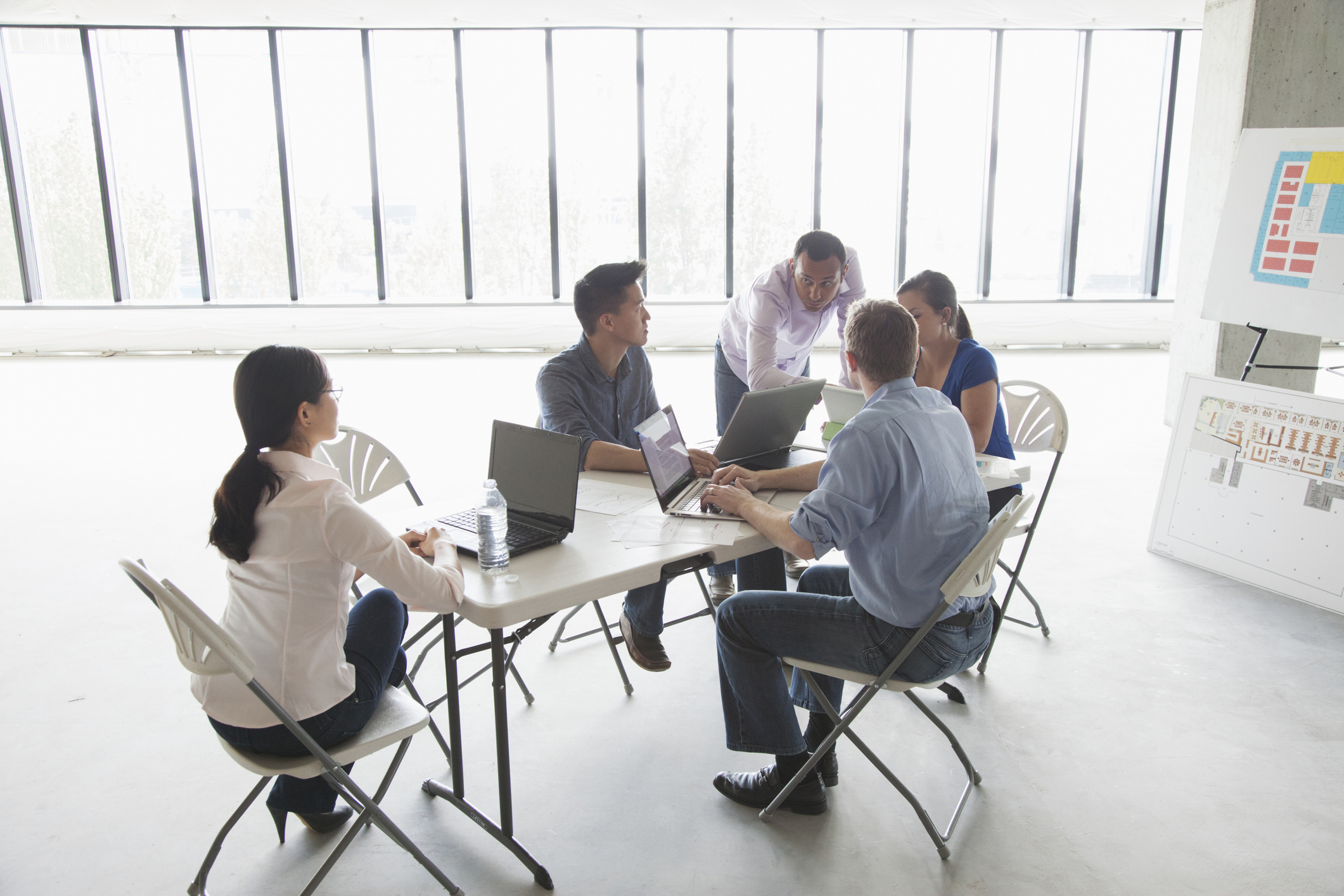 Group of coworkers meeting at a table in an empty office.