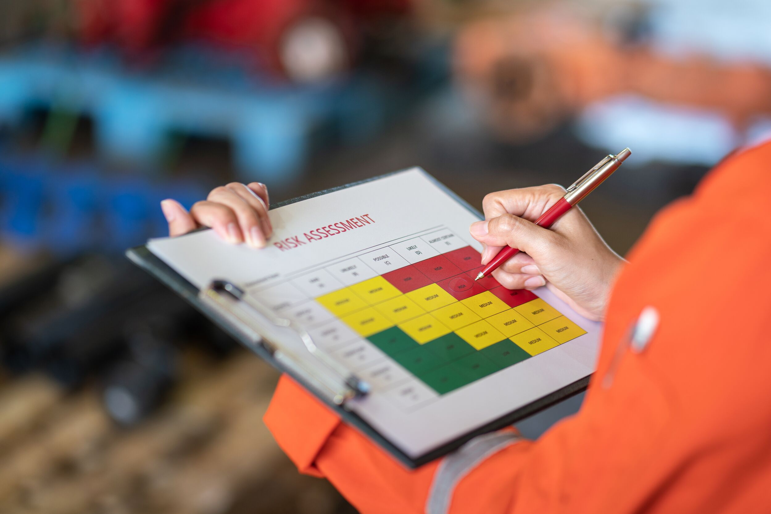Person using ballpoint pen to mark on the risk assessment matrix table at "High risk" level.