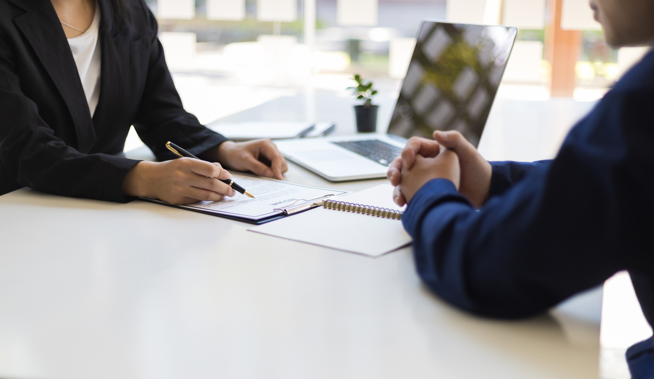 Client and business woman looking over paperwork at a desk.