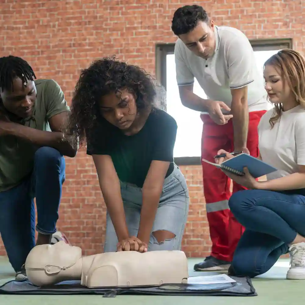 Group looking on as student practices CPR on a dummy.