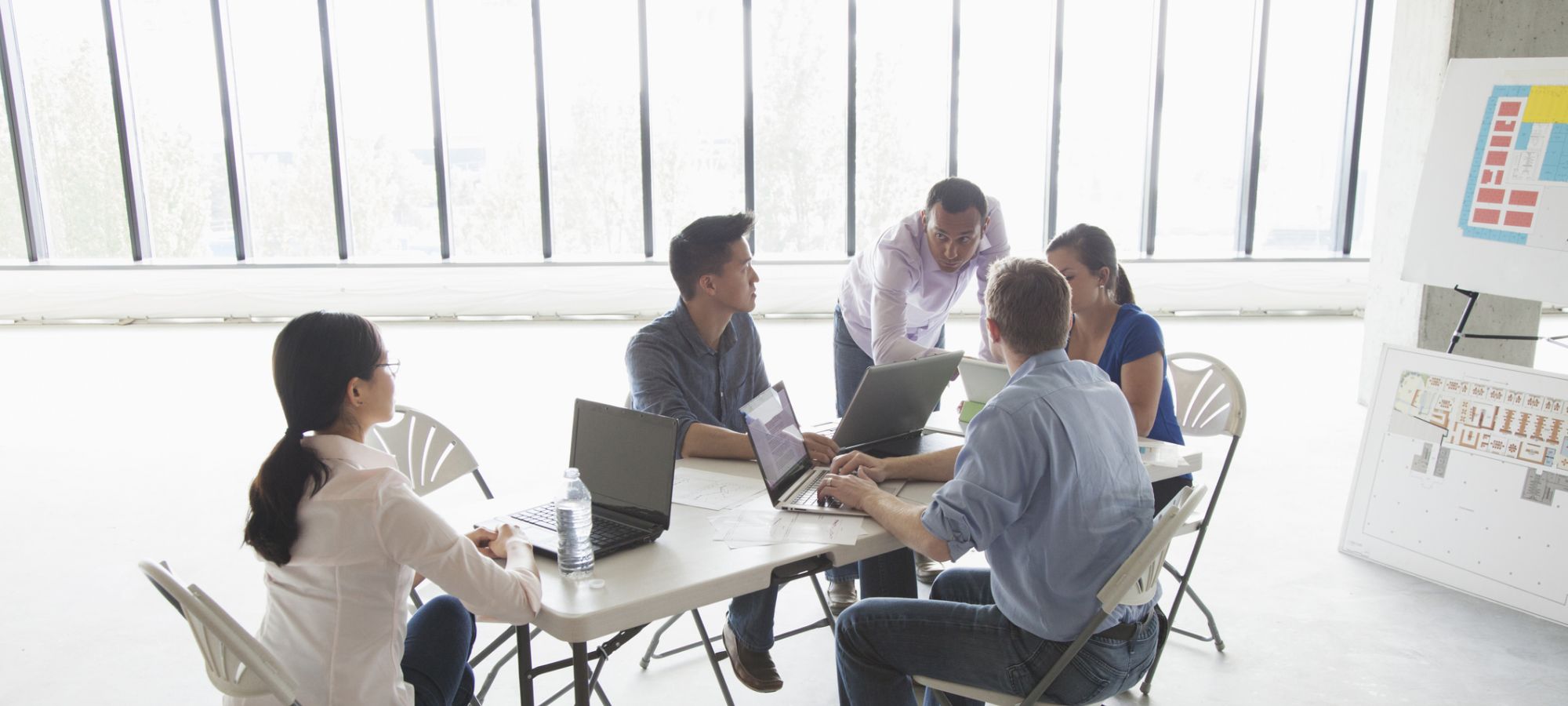 A team of co-workers, sitting at a conference table having a meeting.