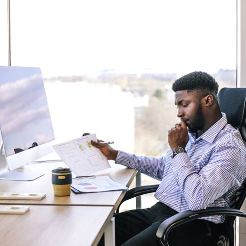 Person sitting at an office desk, holding charts and looking at documents
